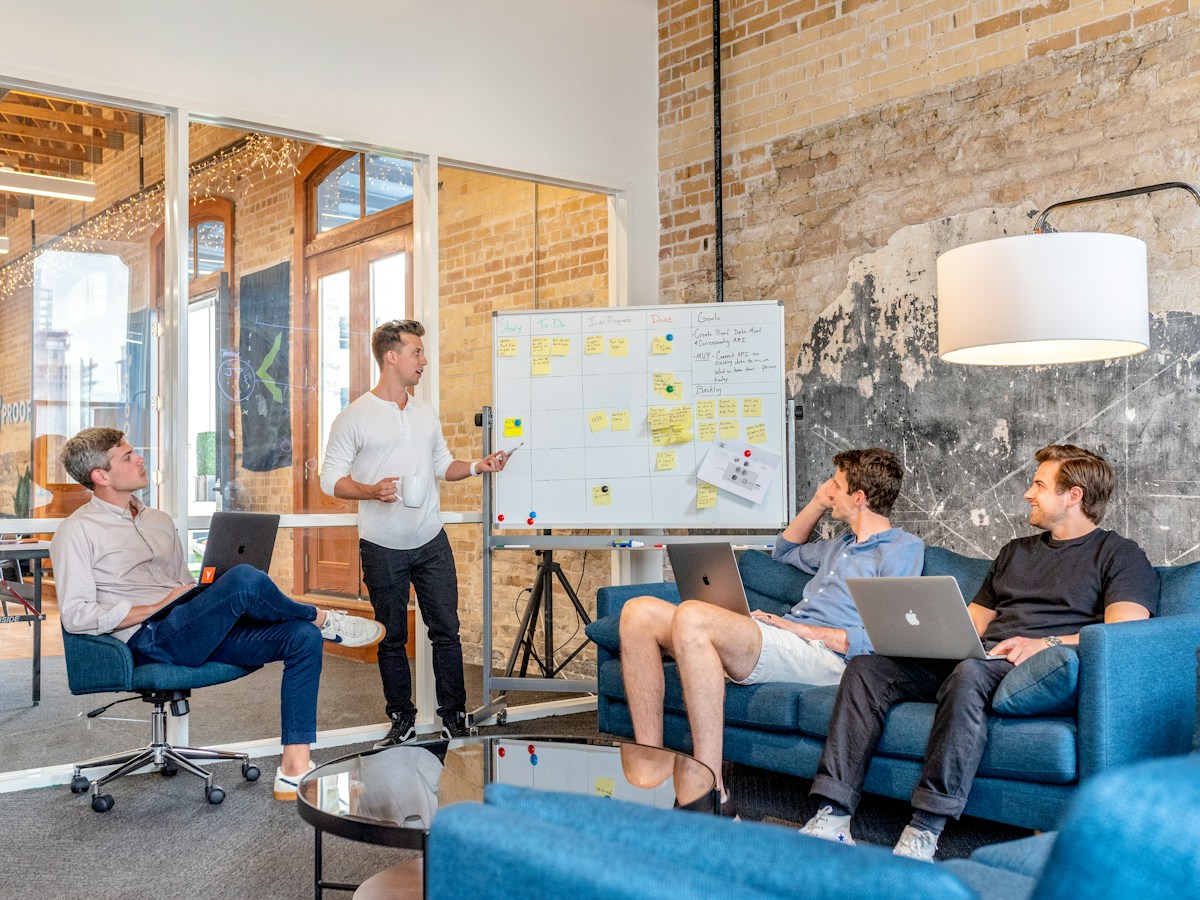 Three men using laptops beside a whiteboard